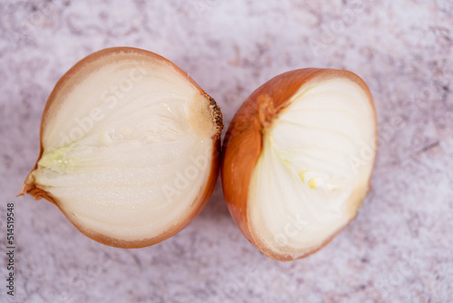 A halved onion on a white stone surface background.