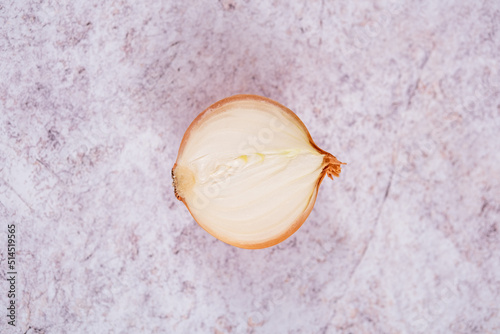 A halved onion on a white stone surface background.