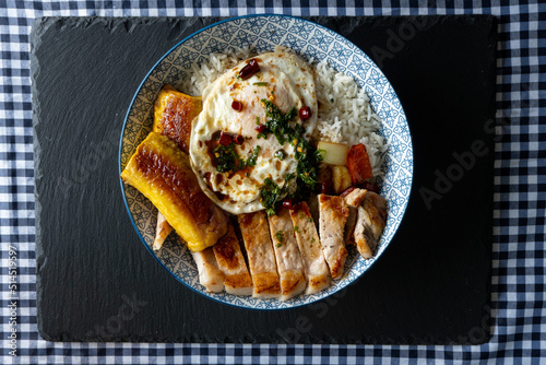 Rice with pork, fried egg, sweet banana and soy sauce 