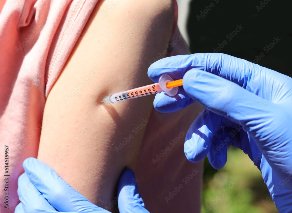 doctor with gloves while administering the vaccine on the arm of the young student during the vaccination campaign doctor with gloves while administering the vaccine on the arm of the young student during the vaccination campaign
