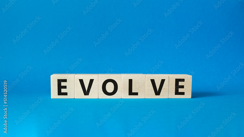Obraz premium Evolve symbol. Concept word Evolve on wooden cubes. Beautiful blue background. Business and Evolve concept. Copy space.