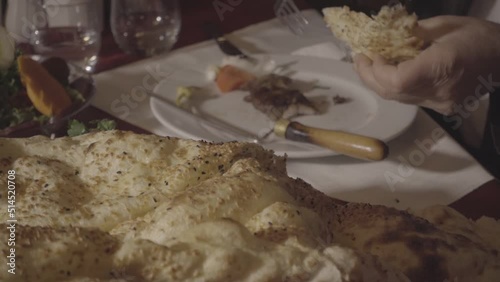 A man who tastes the horizontally cooked kebab typical of Turkish food culture and the products served with it at the dinner table.
