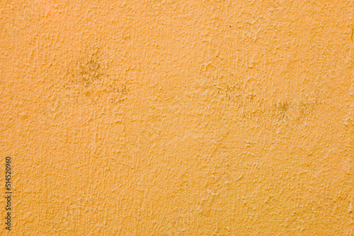 A wall with worn orange plaster.
