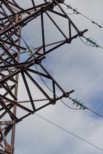 A fragment of a high-voltage transmission line support against the sky.