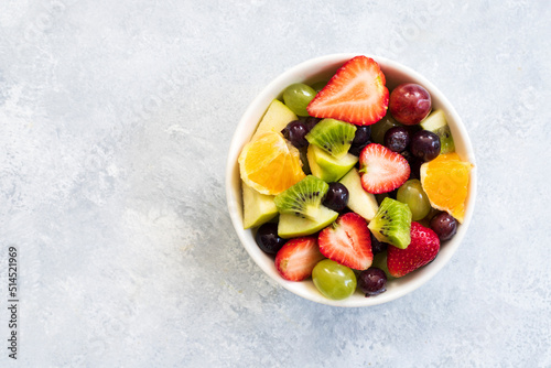 Healthy fresh fruit salad in bowl on gray concrete background. top view. Copy space.