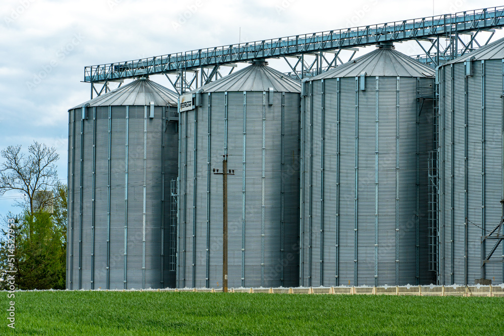 Fototapeta premium silver silos on agro manufacturing plant for processing drying cleaning and storage of agricultural products, flour, cereals and grain. Large iron barrels of grain. Granary elevator