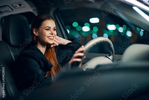 a happy, joyful woman is sitting behind the wheel of a car with a seat belt fastened and smiling happily looking at the road photo