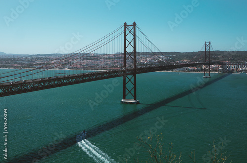 25 de Abril Bridge famous place Lisbon in Portugal. Red bridge, river, boat and cityscape