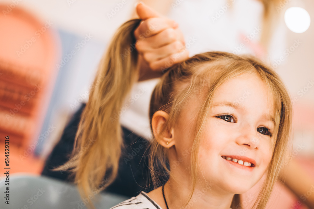 Naklejka premium Stylish little girl in a beauty salon for children where she made a beautiful hairstyle