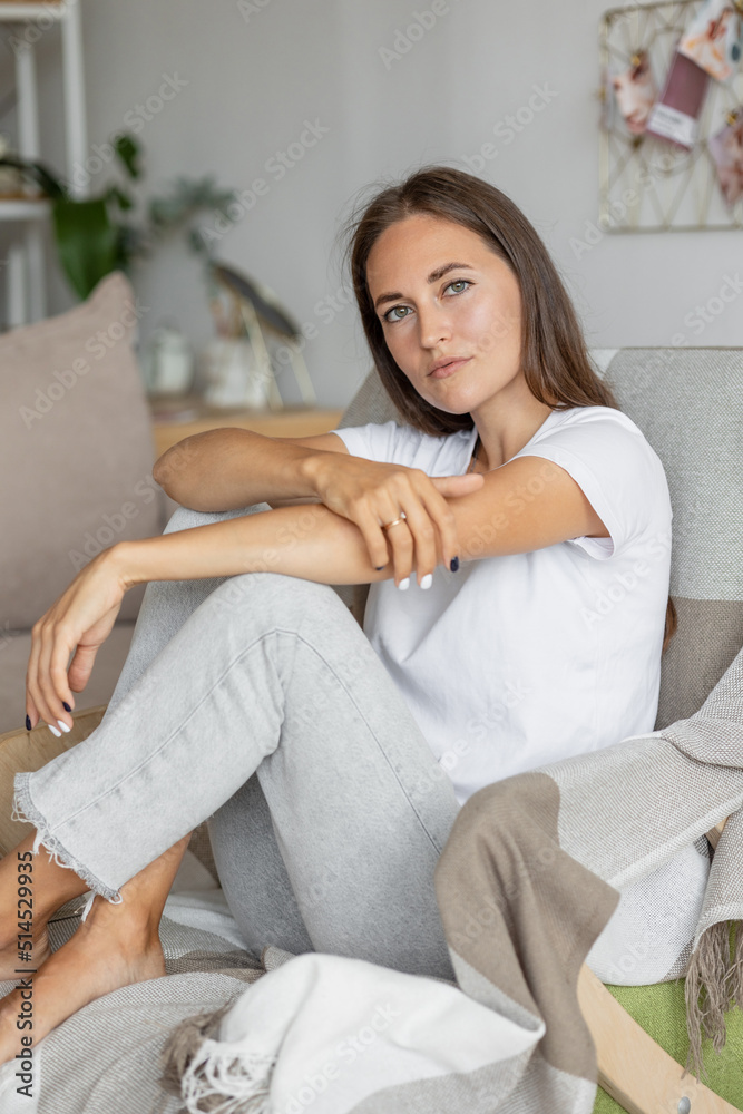 beautiful European woman is at home in the living room resting. A stylish young adult woman with long hair poses and looks at the camera. a day off or vacation for recreation. peace of mind and mental beautiful European woman is at home in the living room resting. A stylish young adult woman with long hair poses and looks at the camera. a day off or vacation for recreation. peace of mind and mental