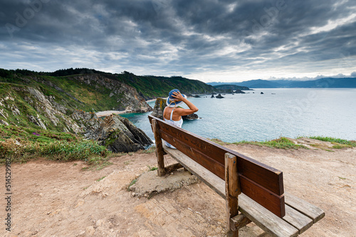 Woman sitting on the famous bench of Mirador de Coitelo, Ortigueira, Loiba Cliffs, Xuncos Coast, La Coruña, Galicia, Spain. photo