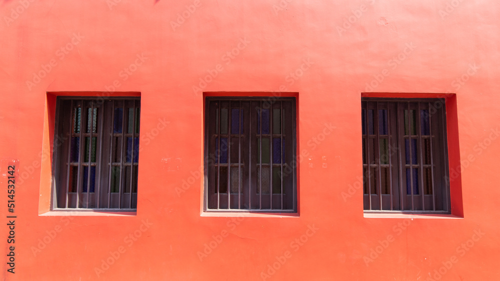 Three windows on a red wall.