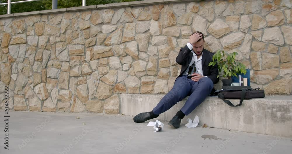 Fired employee holding box of stuff and drinking alcohol