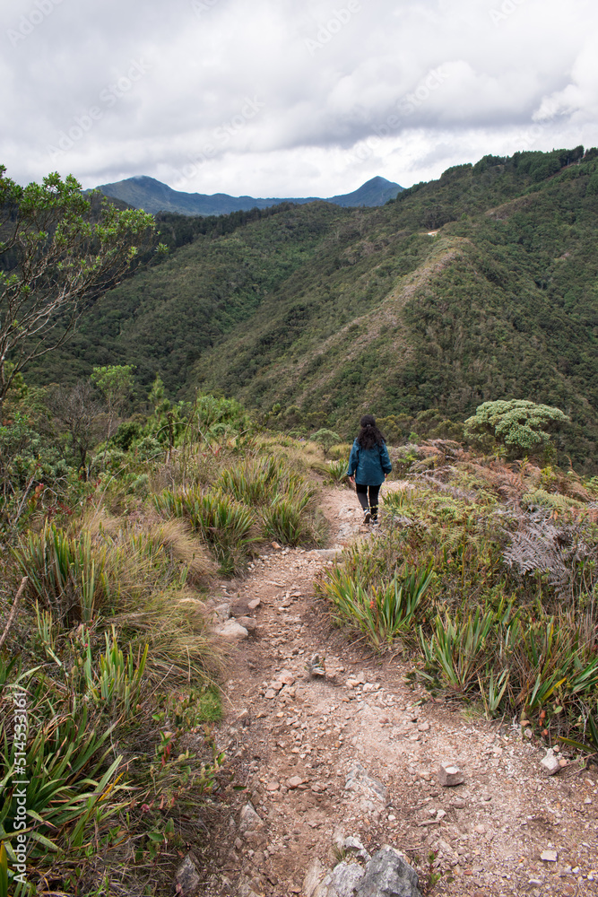 Fototapeta premium Young woman walking on Bogota mountain path through a rocky path