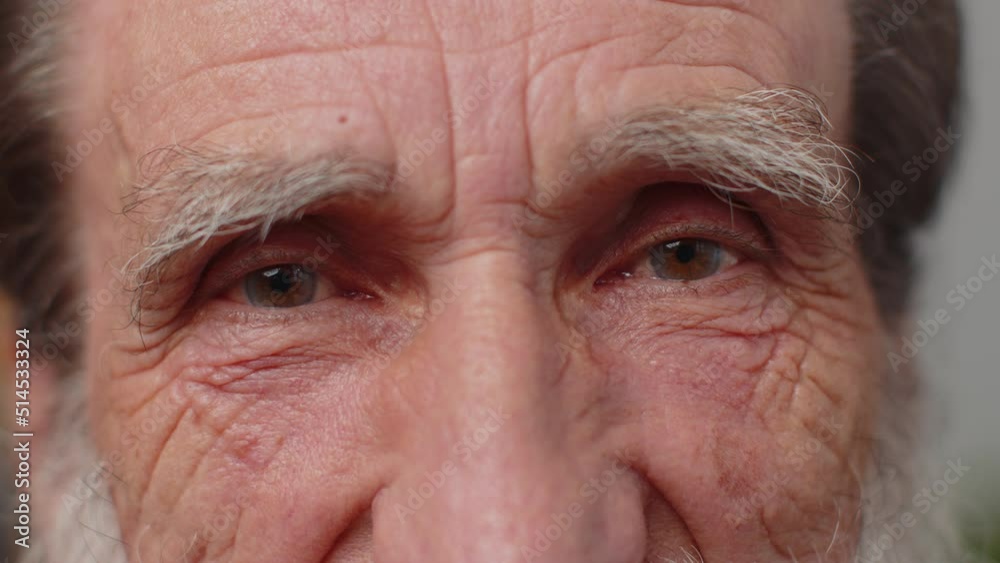 Extreme close-up macro portrait of wrinkled bearded face. Old senior beautiful man's eyes, smiling looking at camera. Brown eyes of elderly guy male model. Mature grandfather opening wide his eyes Extreme close-up macro portrait of wrinkled bearded face. Old senior beautiful man's eyes, smiling looking at camera. Brown eyes of elderly guy male model. Mature grandfather opening wide his eyes