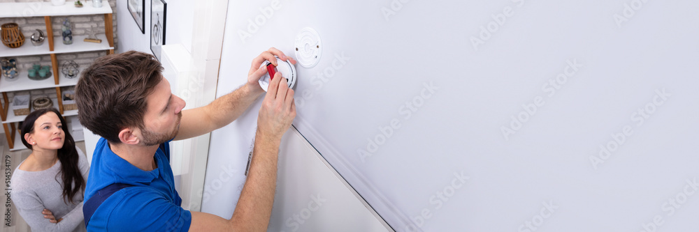 Obraz premium Serviceman Replacing Battery In Smoke Alarm