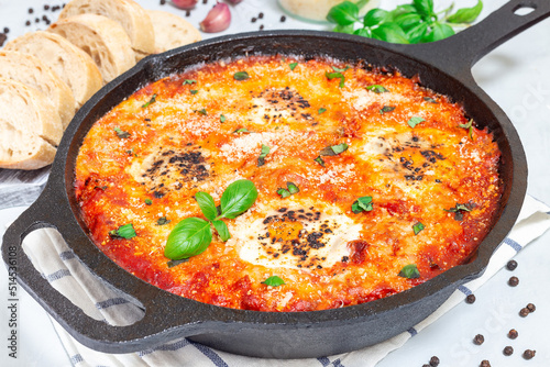 Shakshuka with eggs, Italian sausage, tomato sauce, in cast iron pan, horizontal