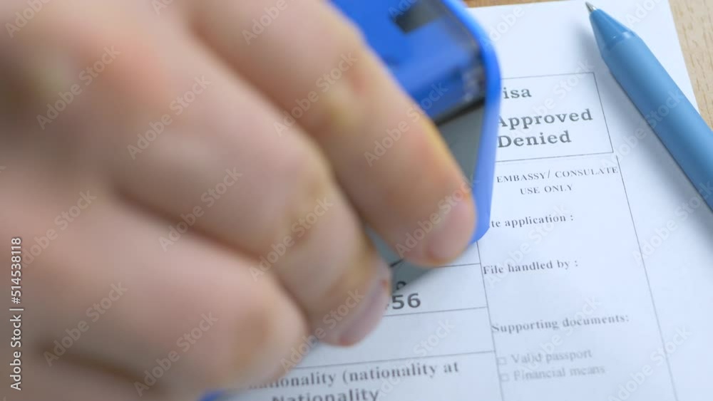 Border officer stamping approved visa decision to grant business visa in application form. Passport and blue pen. Apply and permission for foreigner country. Success interview in embassy