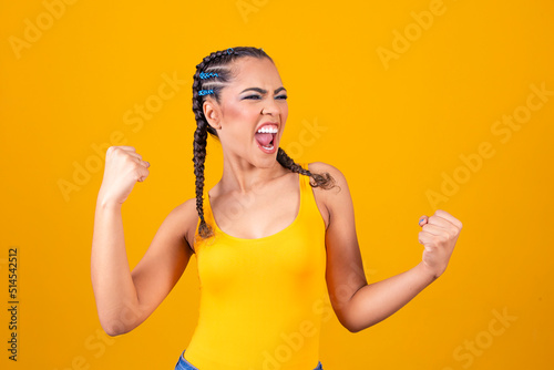 Brazilian supporter. Brazilian woman fan celebrating on soccer or football match on yellow background. Brazil colors.
