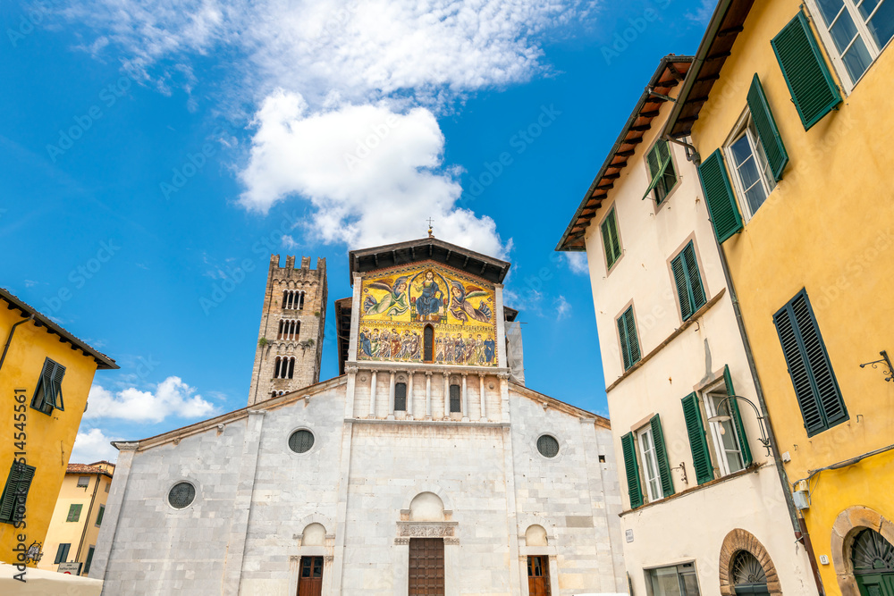 The facade and bell tower of the San Frediano Basilica, a Romanesque church with golden mosaic facade inside the walled medieval town of Lucca, Italy.
