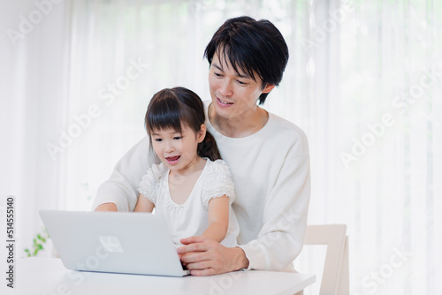 お父さんと一緒にパソコンを使う小さな女の子