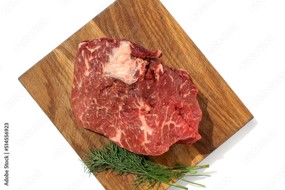 A piece of marbled meat lies on a wooden board.