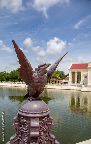 The closeup image of eagle statue. The bokeh background is The Phra Thinang Warophat Phiman or “Excellent and Shining Heavenly Abode” in Bang Pa-In Palace Ayutthaya Thailand.  photo