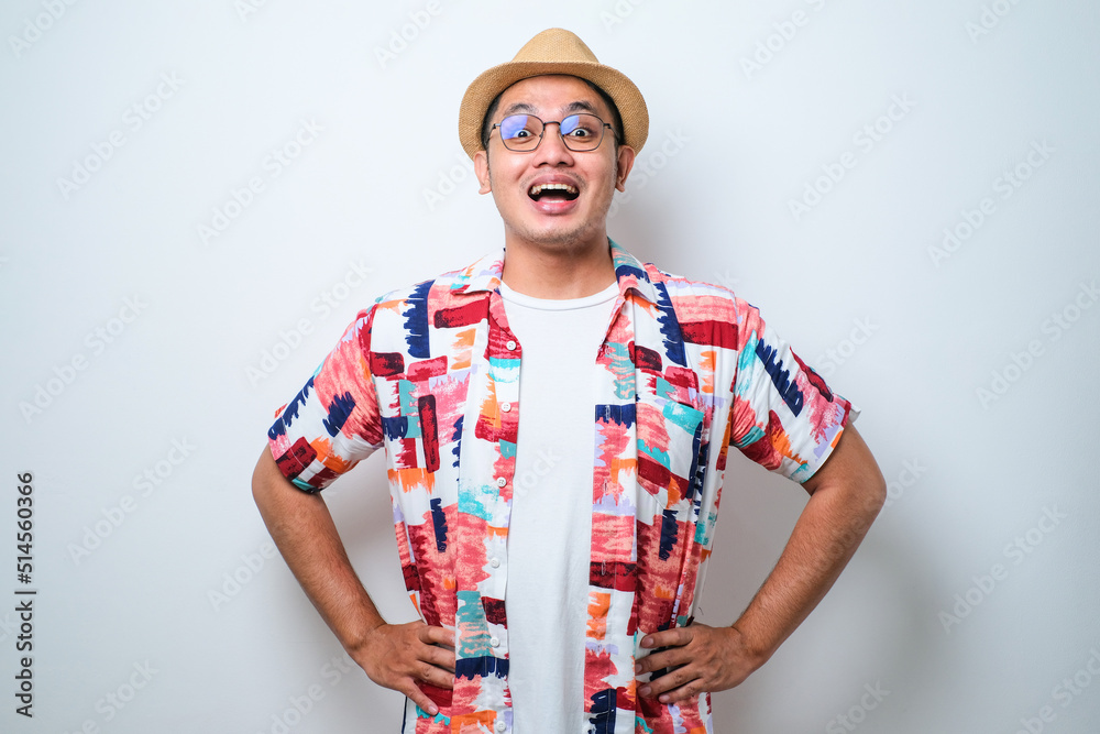 Young handsome Asian traveler man wearing casual beach shirt and bucket hat confident keeping hands, looking at camera on hips