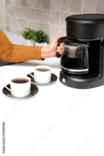 Woman's hands serve coffee prepared in a coffee maker to start the day with the benefits of antioxidants, protects against cancer, fights Alzheimer's and Parkinson's 