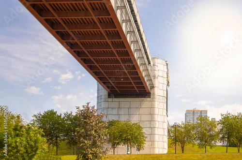 Engineering design of the metro bridge with concrete supports, bottom view. Panorama of the city with sky and trees © clairelucia