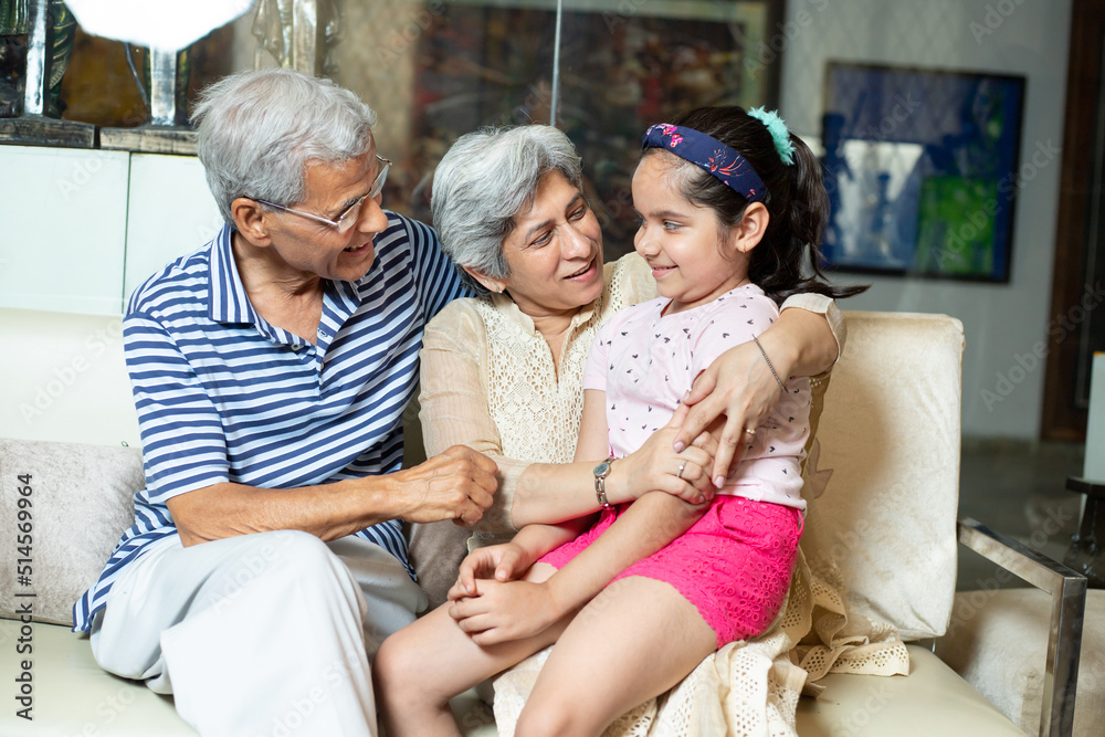 Happy indian grandparents spend time with grandchild, Asian senior retired people sitting together at granddaughter taking and having fun,