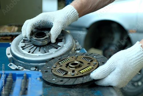 Maintenance of a passenger car in a service center. A clutch kit is in the hands of an auto mechanic. Control of compliance and integrity of the drive disc, the driven disc and the exhaust bearing. photo