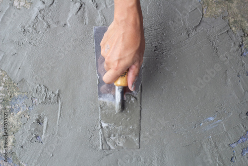 Top view of Hand of worker holding plastering trowel by leveling the concrete floor smooth. Repairing old rough floors. photo