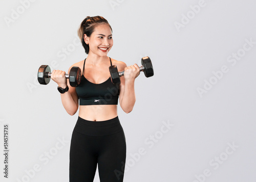 Woman playing dumbbells in gym clothes isolated on gray background. Beautiful fitness model doing exercise for health