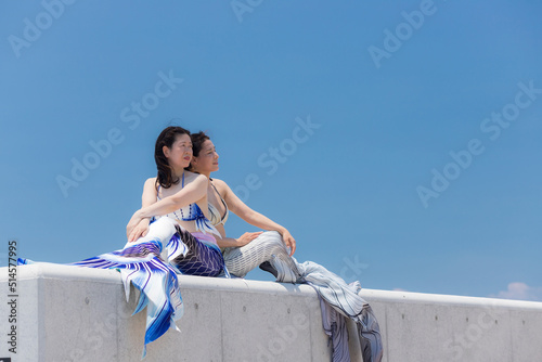 夏の海の海岸でマーメイドを練習して遊んでいる二人の女性の姿