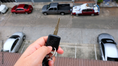 Female holding car keys with car on background.