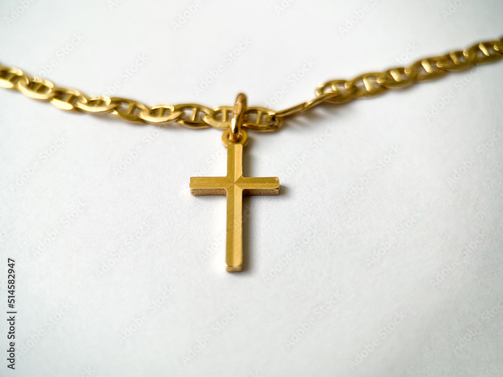 Gold cross on a gold chain close-up on a white isolated background