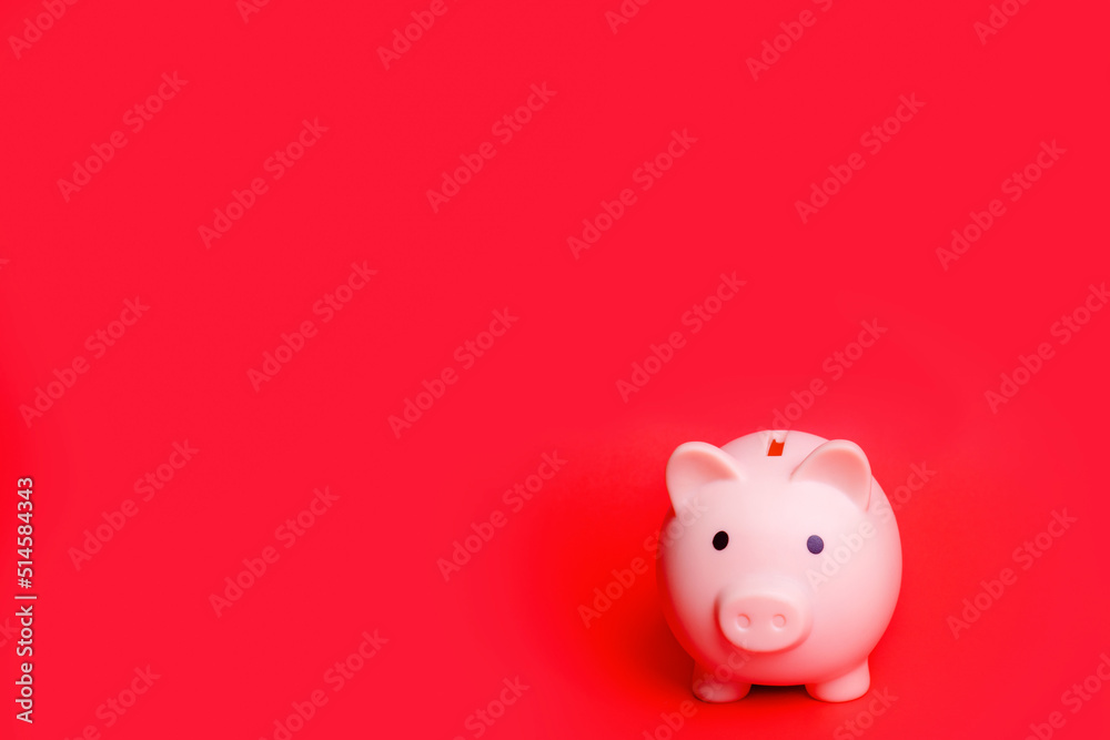 Pink piggy bank isolated against red background