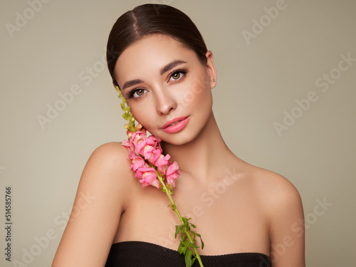 Portrait beautiful young woman with clean fresh skin. Model with healthy skin, close up portrait. Cosmetology, beauty and spa. Girl with a pink  flower photo