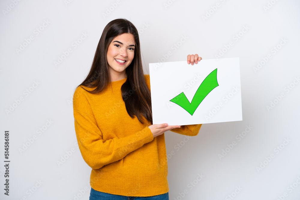 Young Brazilian woman isolated on white background holding a placard with text Green check mark icon with happy expression Young Brazilian woman isolated on white background holding a placard with text Green check mark icon with happy expression