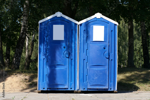 Two portable toilet cabins in park at dry sunny summer day © Valeriy