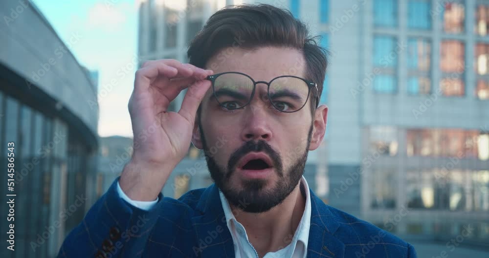 A shocked man with glasses and shirt saying wow cover your mouth with your hand.