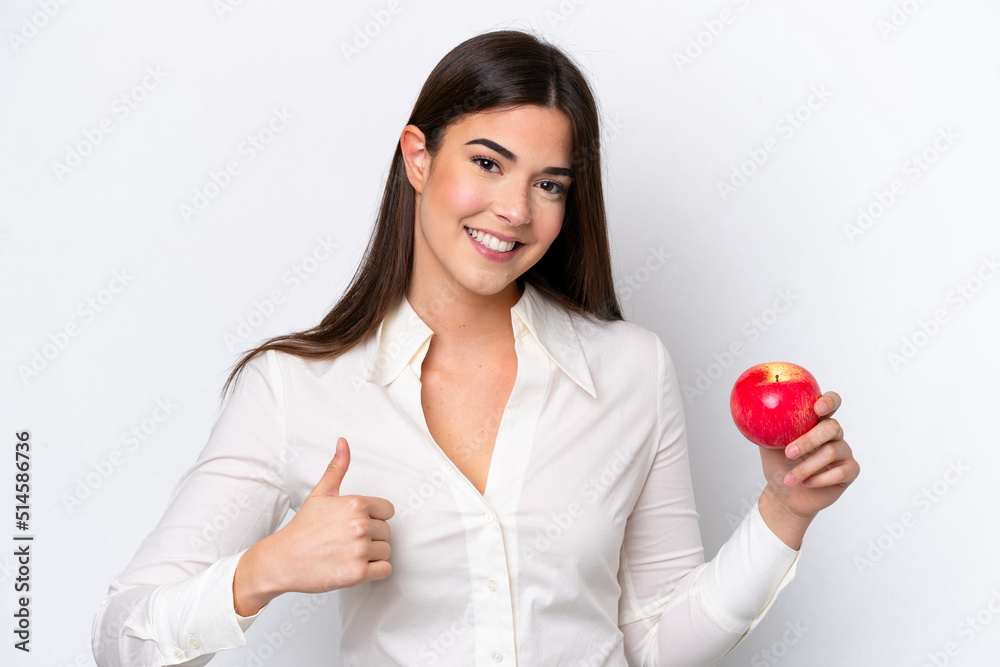 Young Brazilian woman with an apple isolated on white background with thumbs up because something good has happened Young Brazilian woman with an apple isolated on white background with thumbs up because something good has happened