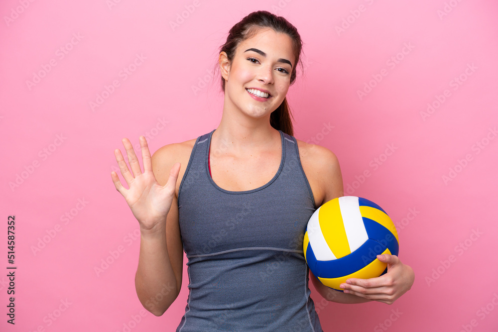 Young Brazilian woman playing volleyball isolated on pink background counting five with fingers