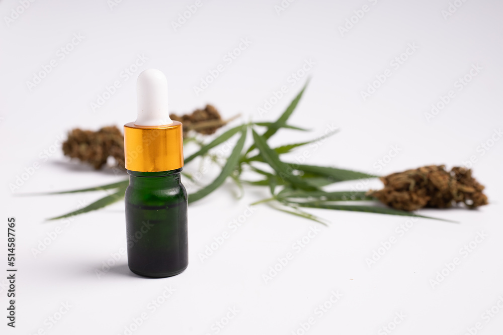 Various glass bottles with CBD oil, THC tincture and hemp leaves on a white background.