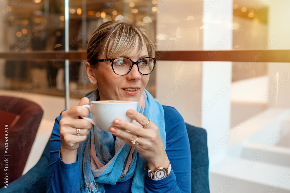 age woman in a blue blouse and scarf drinking coffee in the cafe and have a chat age woman in a blue blouse and scarf drinking coffee in the cafe and have a chat