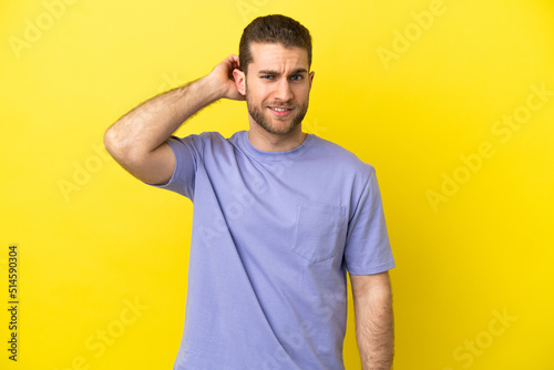Handsome blonde man over isolated yellow background having doubts
