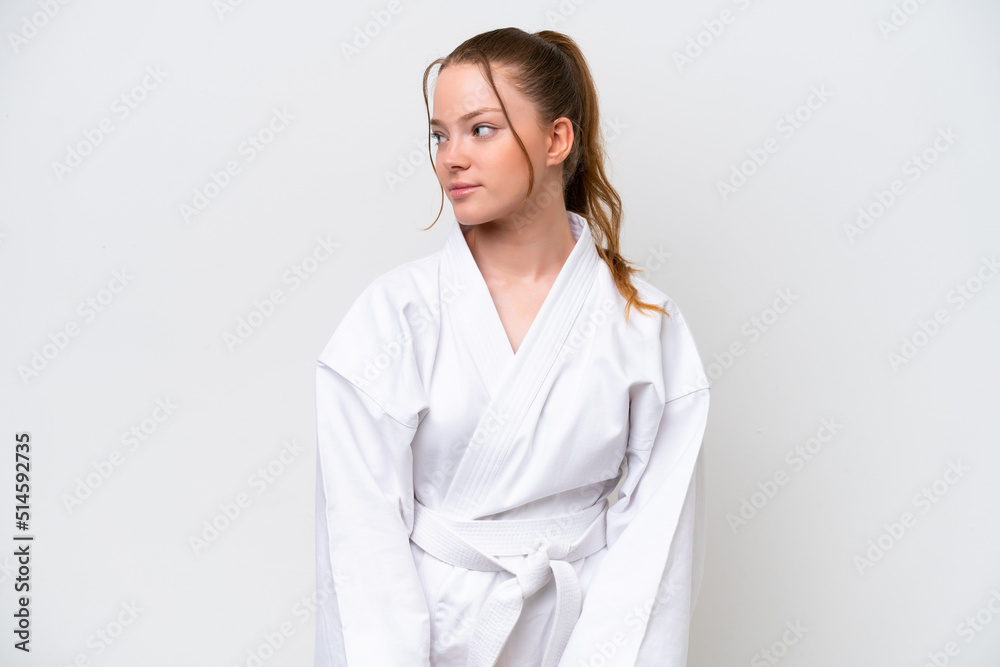 Young caucasian girl doing karate isolated on white background looking to the side Young caucasian girl doing karate isolated on white background looking to the side