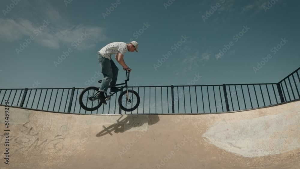 Urban extreme sport BMX. A man performs tricks in a skate park, on a ramp.