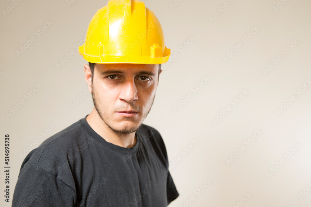 Worker with yellow safety hat for construction site work. Young white caucasian man with short hair and dark eyes.